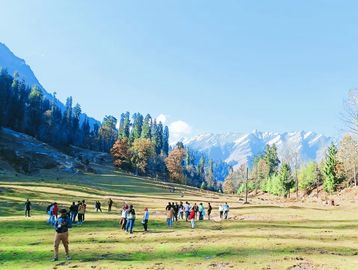 Group of people exploring a scenic mountain valley on a sunny day.