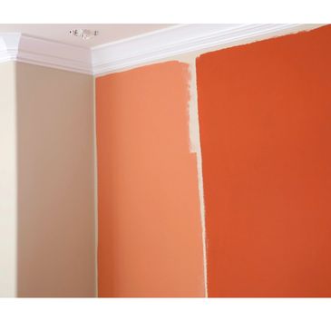 Interior wall painting with two bold shades of orange and crisp white crown molding, showing a profe