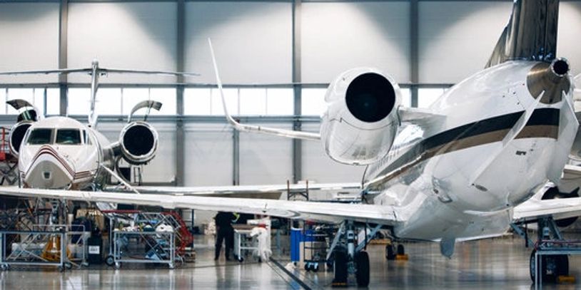 Two private jets parked inside a spacious aircraft hangar.