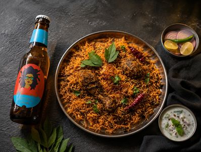 Spicy chicken biryani with a bottle of beer.