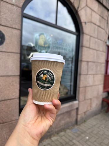 Hand holding a Tartan Tattie's coffee cup.