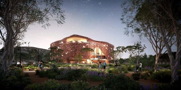 A modern building with star-shaped lights surrounded by a garden at dusk.