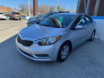 Silver Kia sedan parked outside on a sunny day.