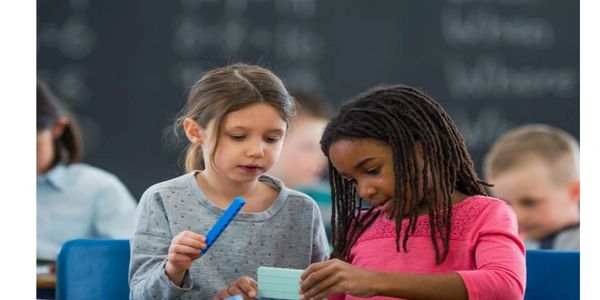 Two young girls collaborating on a classroom task with focus and curiosity.