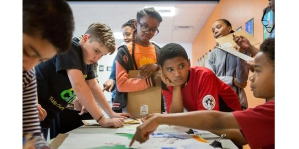 Students engaged in a collaborative classroom activity around a table.