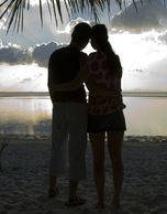 A young man and woman staring at the sunset.