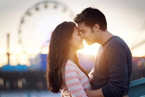 Two young adults in love at an amusement park.