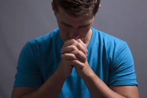 A young man bowing his head in prayer.