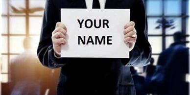 Person in suit holding a sign that says 'YOUR NAME'.