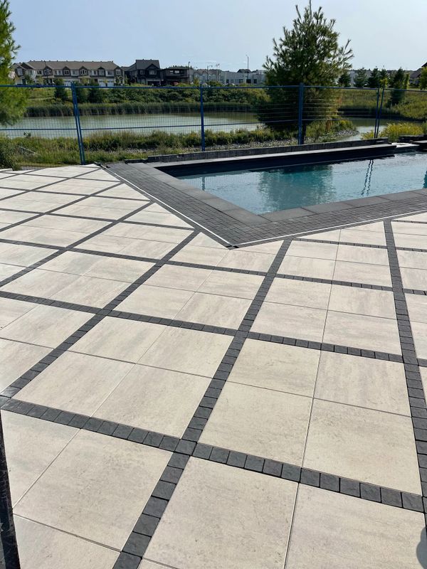 Backyard interlock striped pattern with pol and pond behind - Techo Bloc