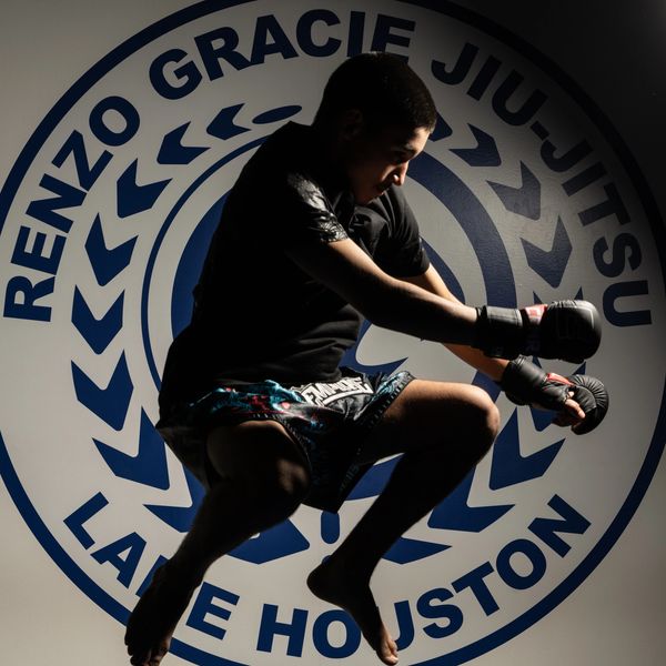 Martial artist in mid-air jump at Renzo Gracie Jiu-Jitsu Houston gym.
