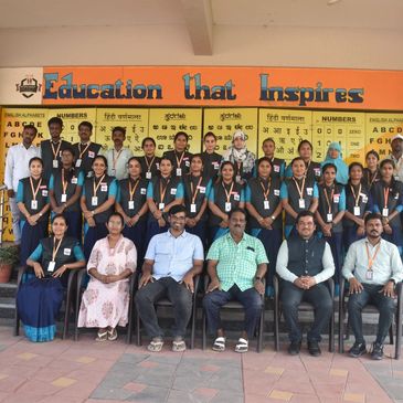 Group photo of educators and students in front of an educational board.