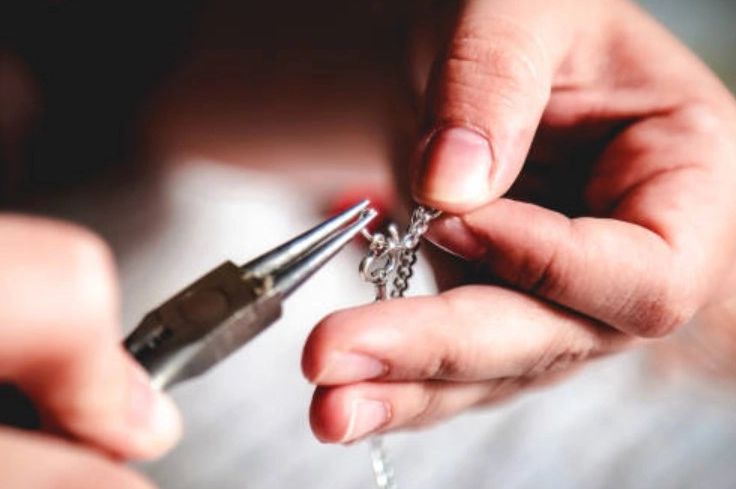 up close of hands working to fix a piece of jewelry.