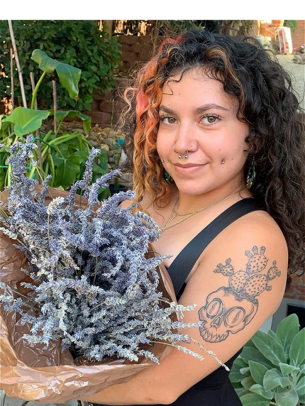 An Indigenous woman holding a Lavender bouquet with plants in the background