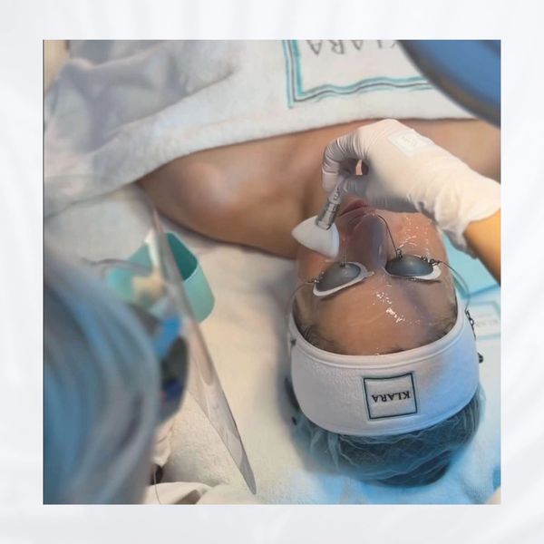 A person receiving a facial treatment with eye protection and skincare device.