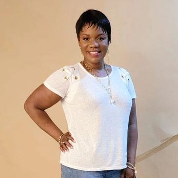 Woman smiling with hand on hip in casual outfit.
