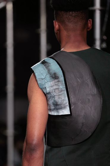 Back view of a person wearing a textured, cracked-patterned garment.