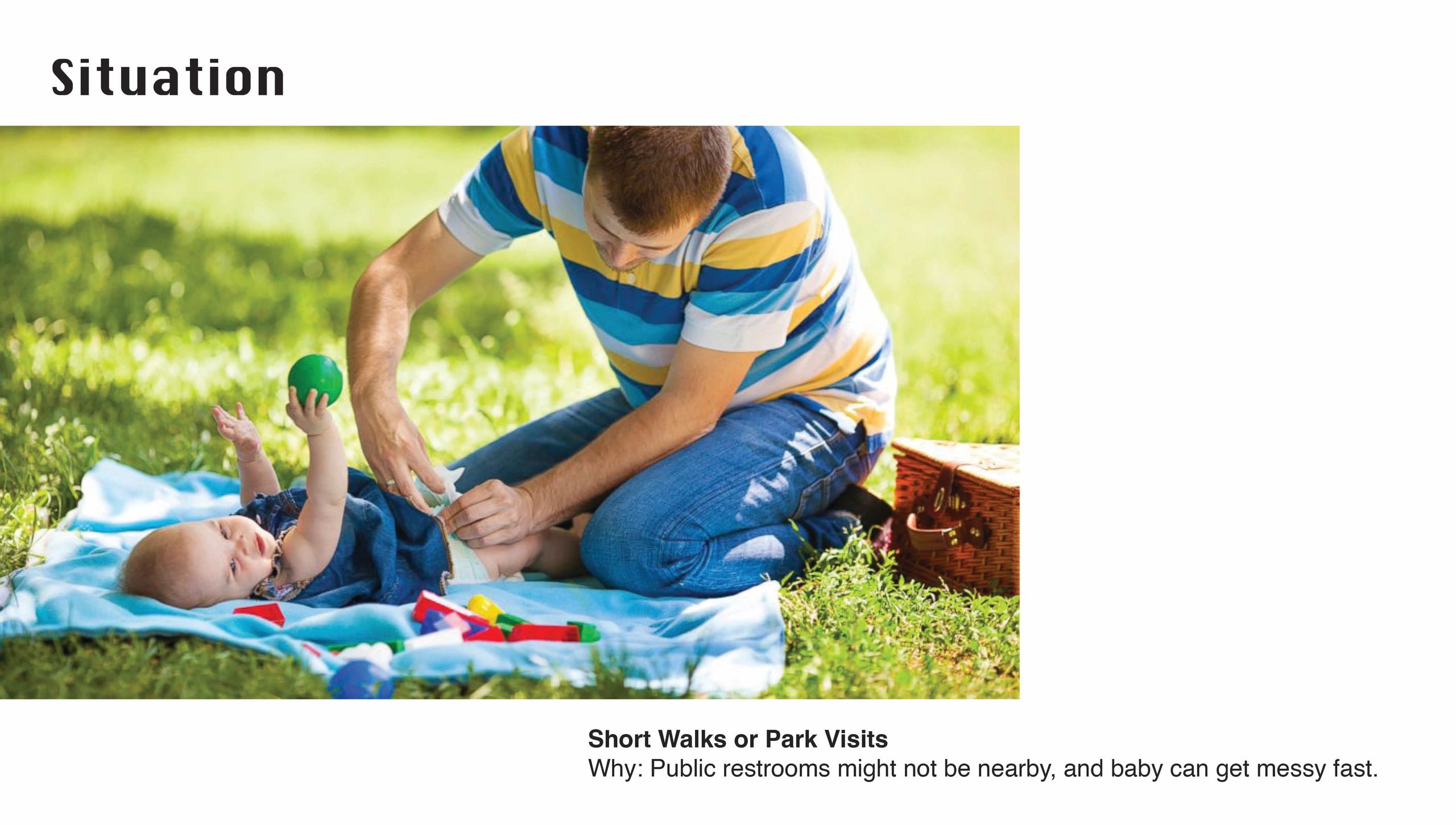 Father changing baby's diaper outdoors during a park visit.