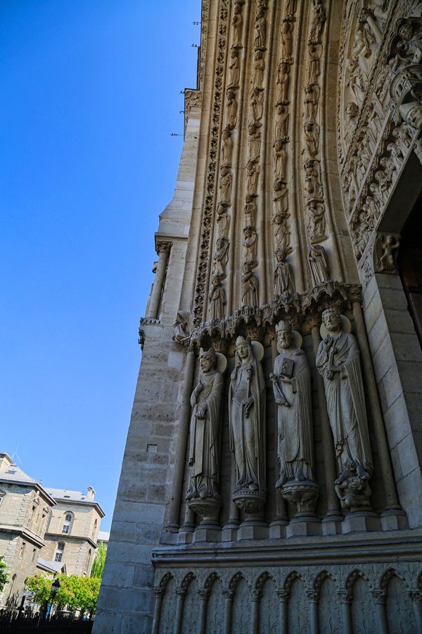 Stone statues on a cathedral facade under clear blue sky.