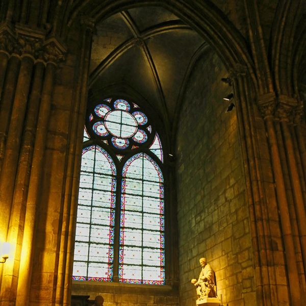 Gothic stained glass window and statue inside a cathedral.