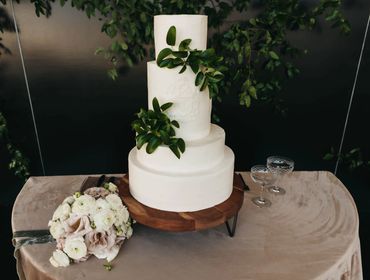 Wedding Cake with Custom Crest on Wood Stand with Velvet Linen & Foliage