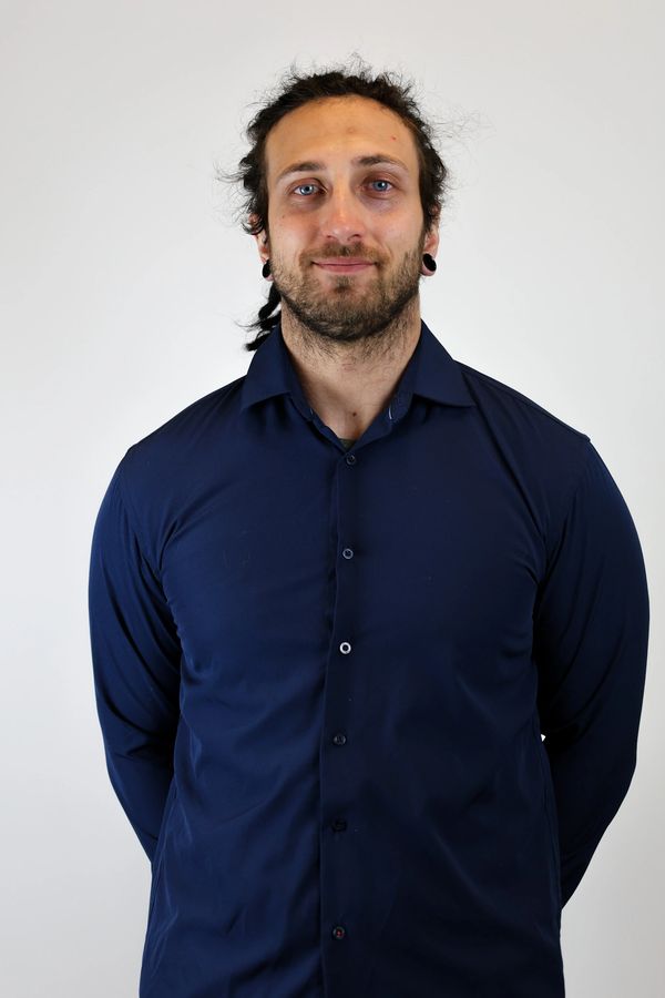 Man with braided hair and navy blue shirt smiling.