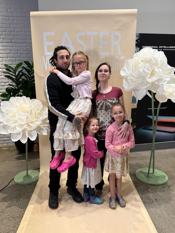 Family posing for Easter church photo with large white flowers.
