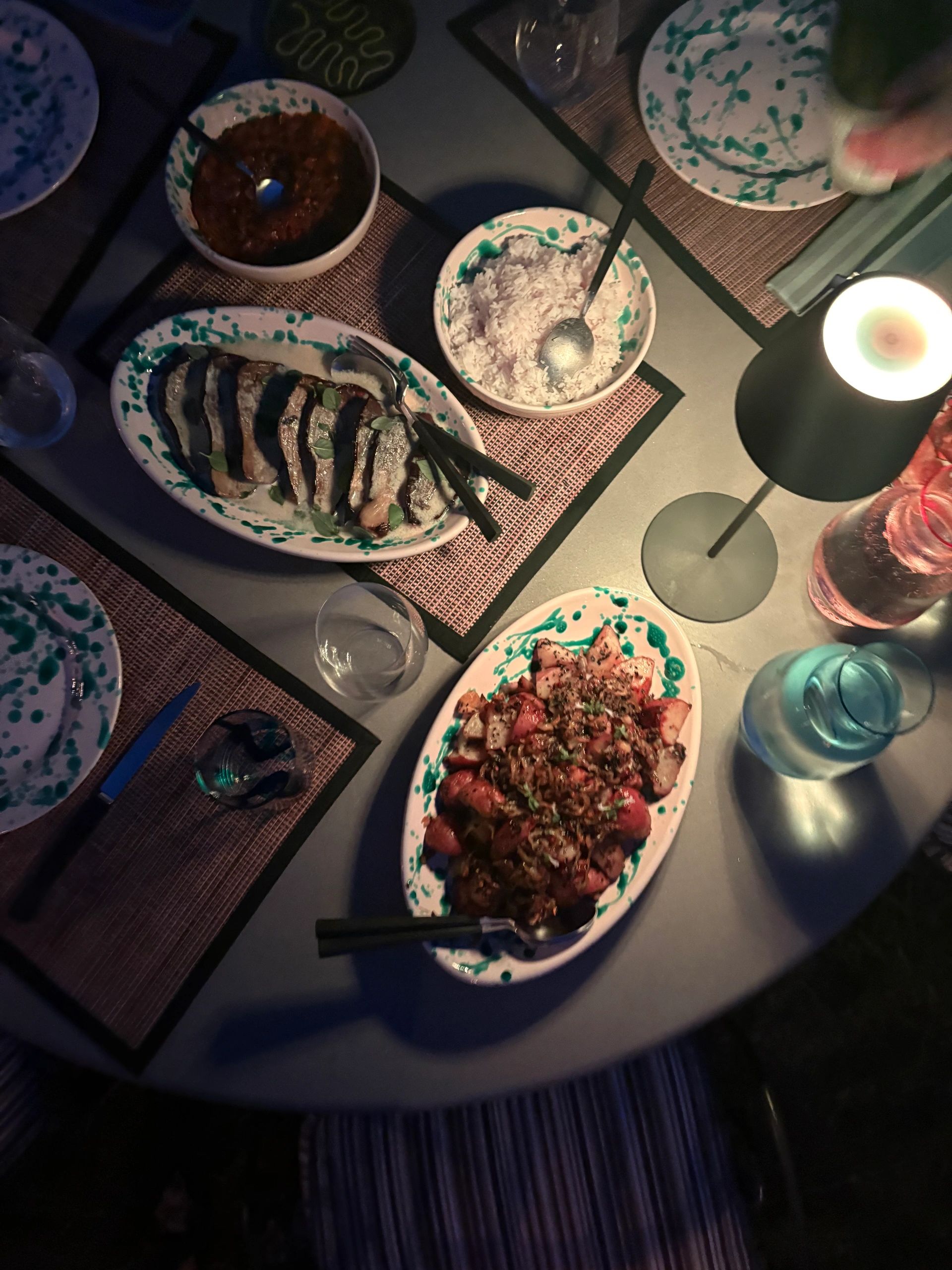 Dinner table with plates of food and rice under dim lighting.
