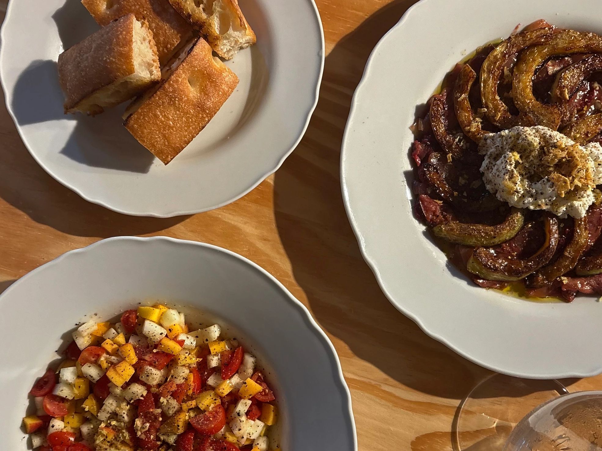 Bread, salad, and roasted vegetables on plates.