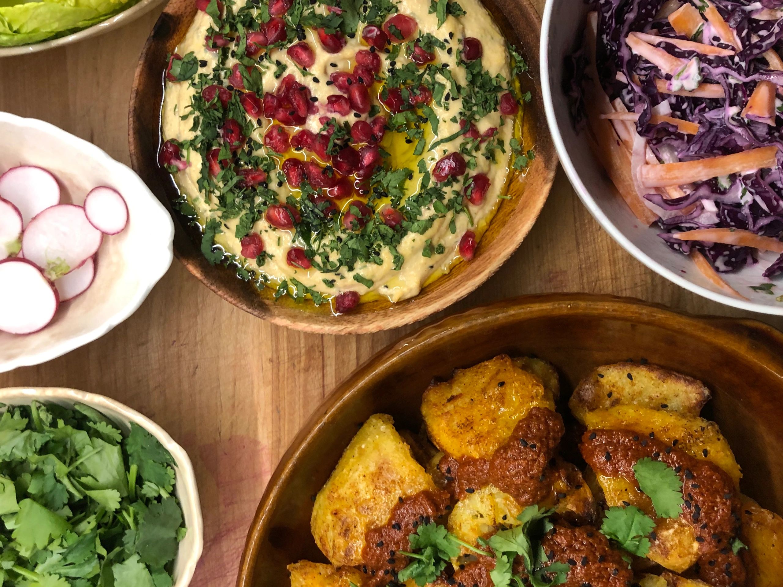 Assorted Middle Eastern dishes with hummus, radishes, herbs, and grilled items.