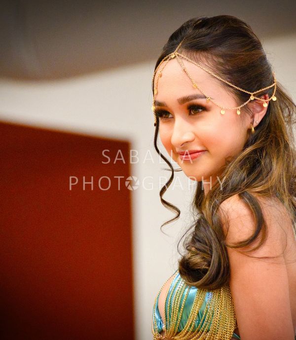 Woman with golden headpiece and styled hair.