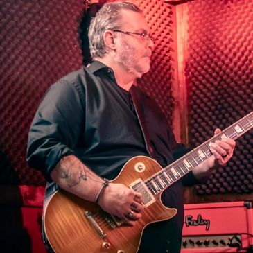 Man playing electric guitar in a soundproof room.
