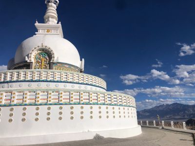 White Buddhist stupa under a blue sky.