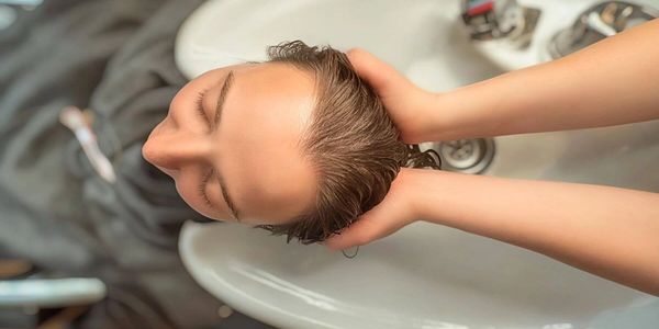 Woman in NYC getting her hair washed and head massaged. The professional uses both hands to massage.