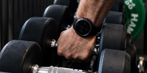 Hand gripping a dumbbell in a gym.
