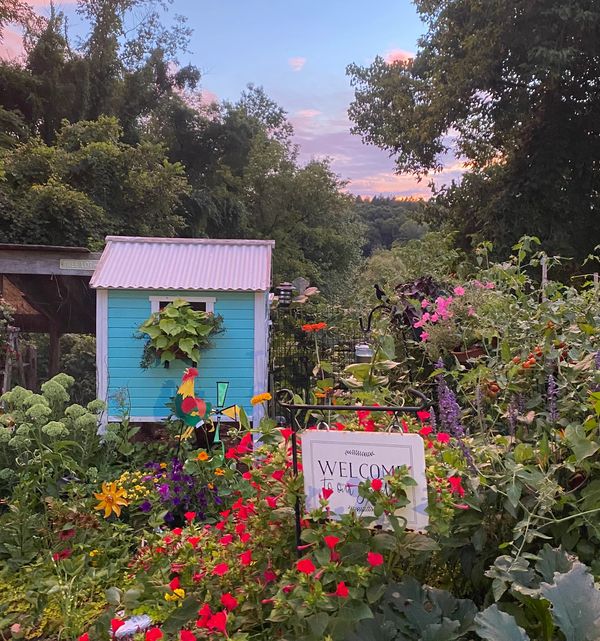 Little Blue chicken coop surrounded by flowers