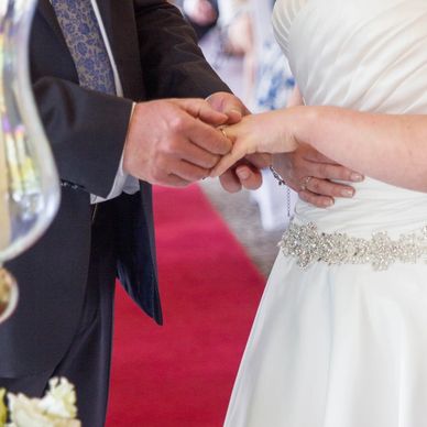 A groom placing a wedding ring on the bride's finger during a ceremony.
