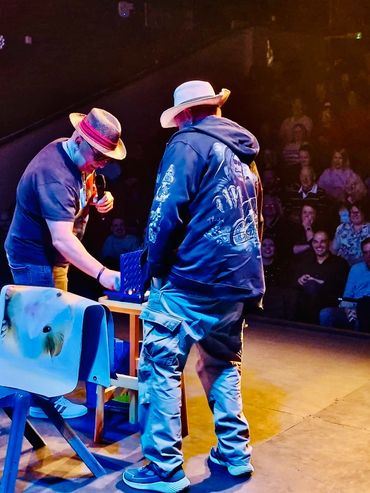 Two men playing a board game on stage in front of an audience.