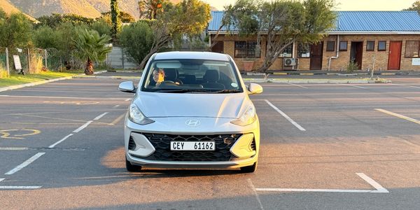 Front view of a white Hyundai car parked in an empty parking lot.