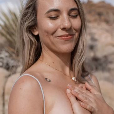 A serene woman with closed eyes smiling gently outdoors.