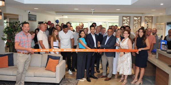 Group of people at a ribbon-cutting ceremony indoors.