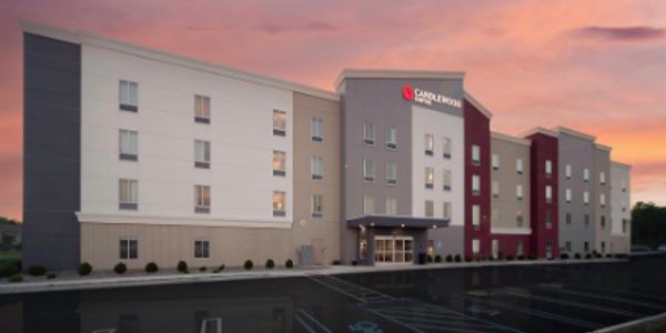 Exterior view of a four-story Candlewood Suites hotel at sunset.