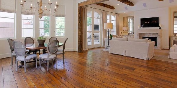 Variable plank size solid wood flooring living and dining area with hand hewn exposed wood beams