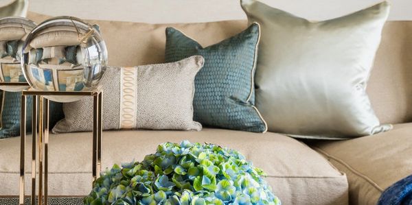 Elegant living room styled with beige sofa, blue pillows, and a floral centerpiece on a coffee table.