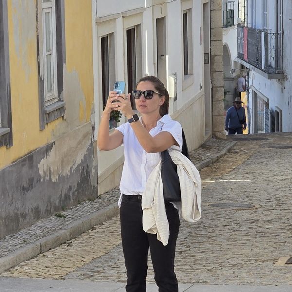 Woman taking a photo on a cobblestone street.
