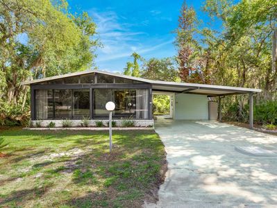 Modern single-story house with large windows and carport.
