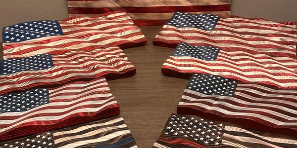 Multiple wooden American flags arranged on a wooden surface.