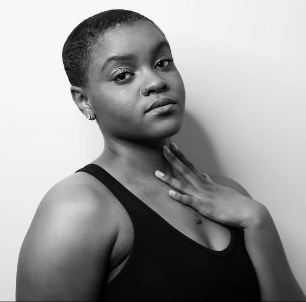 Black and white portrait of a confident woman with short hair and a nose ring.