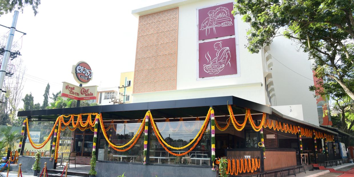 Decorated Cake Wala restaurant building with vibrant flower garlands.