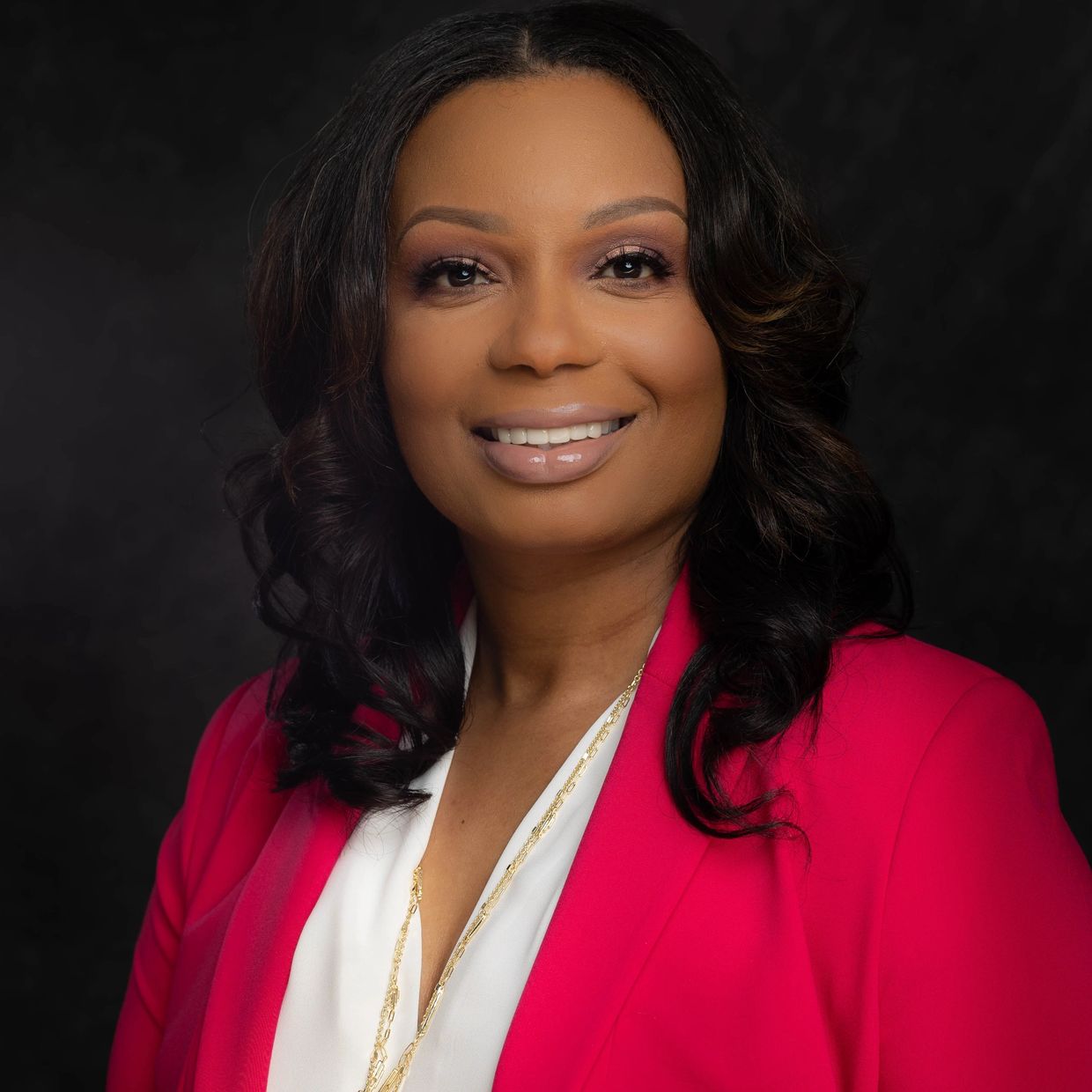 A Picture of Tara smiling with a red blazer and white shirt on. 